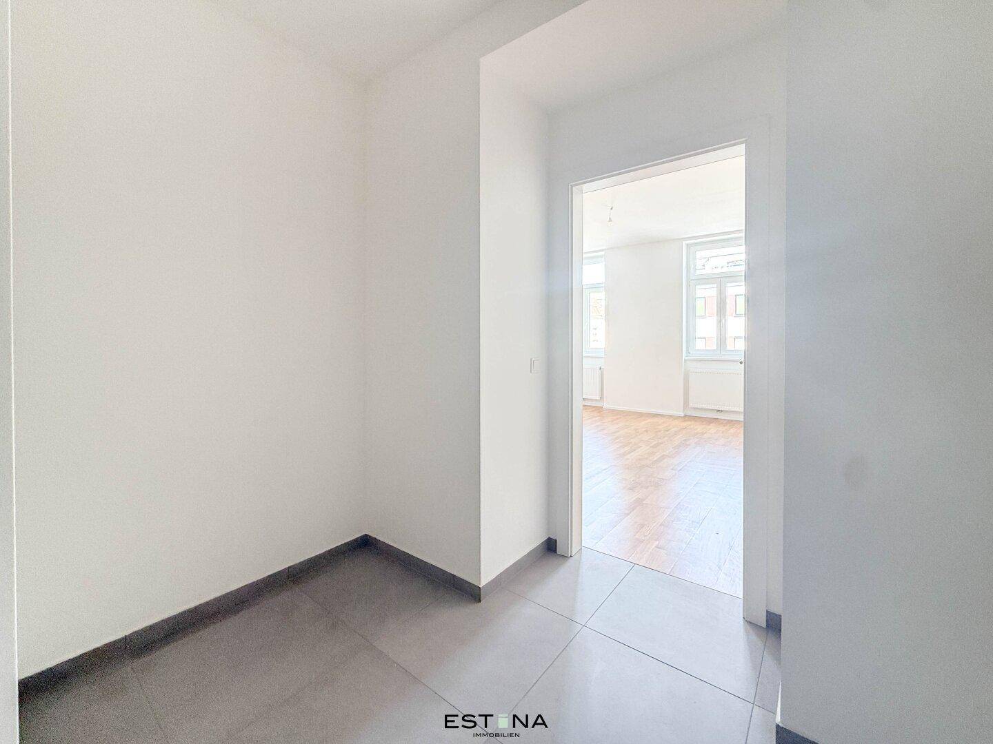 Heller Flur mit modernen Fliesen und Zugang zu weiteren Räumen der Wohnung.