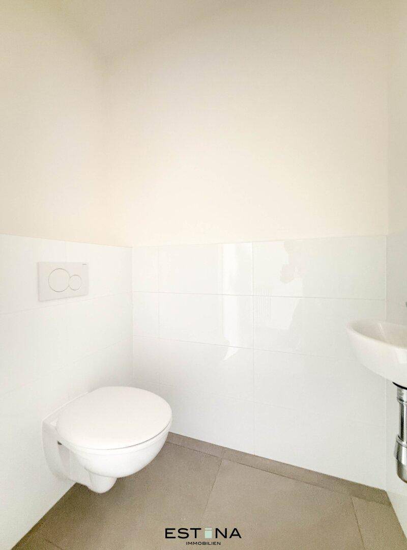 Separates Gäste-WC mit wandhängender Toilette und kleinem Waschbecken, sauber und funktional.