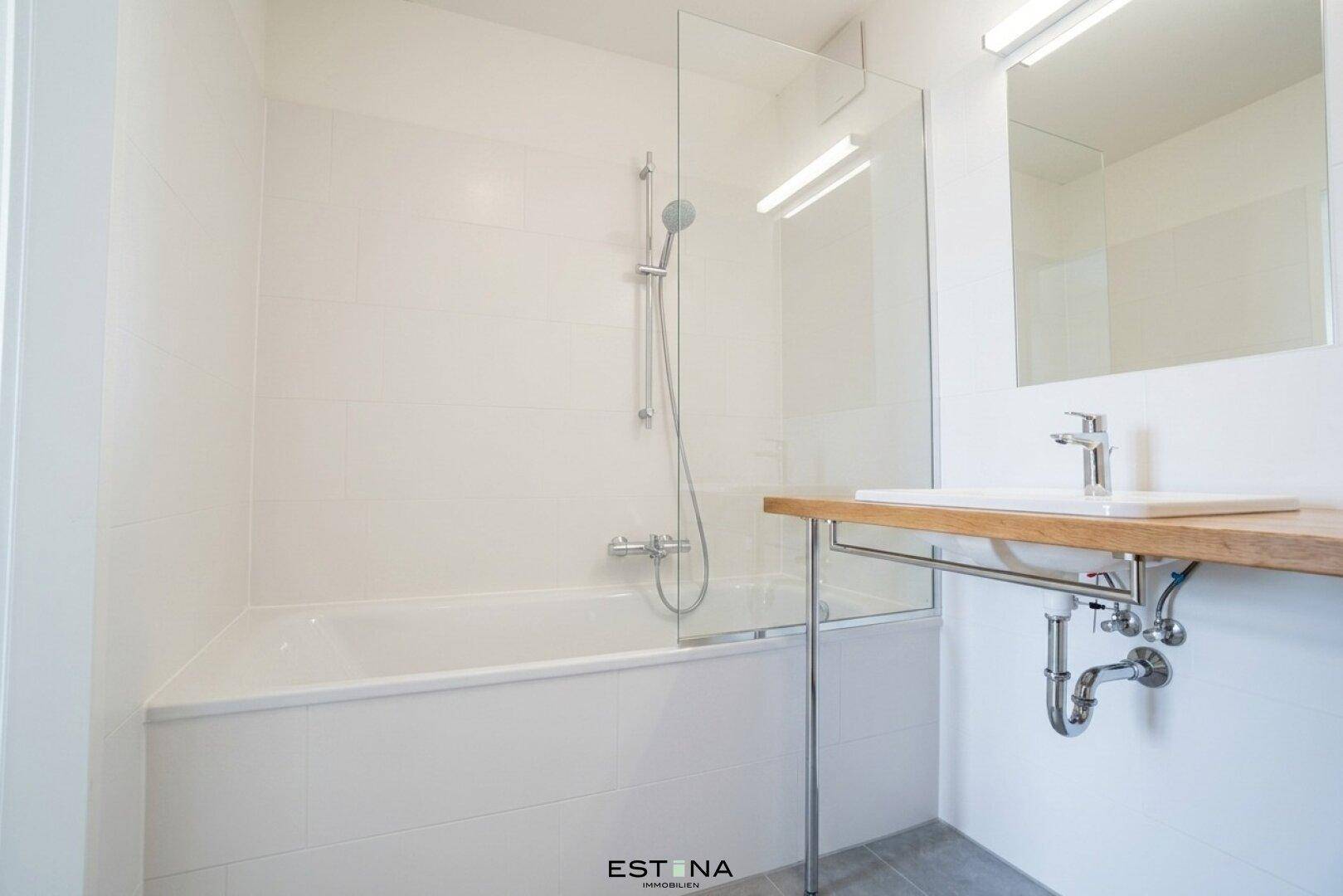 Modernes Badezimmer mit Badewanne, Duschabtrennung, Einzelwaschbecken und Holzablage.