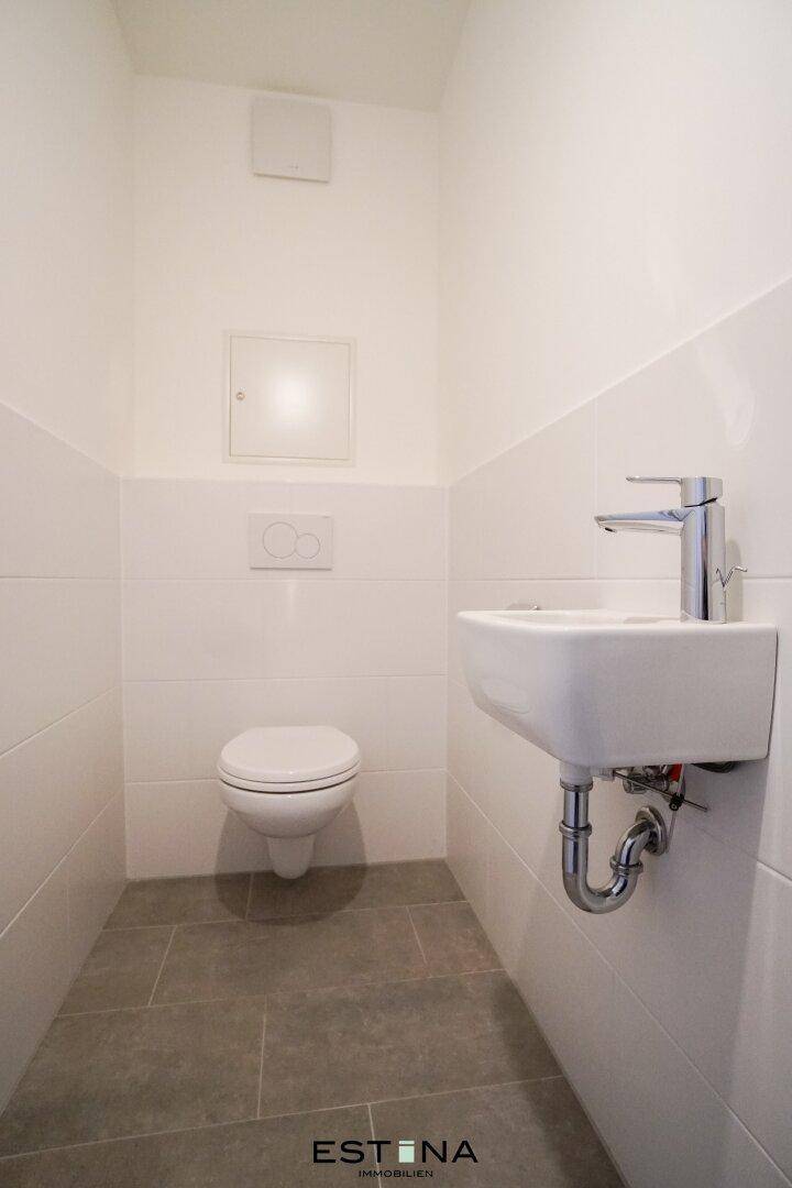 Separates Gäste-WC mit Wand-WC und kleinem Waschbecken.