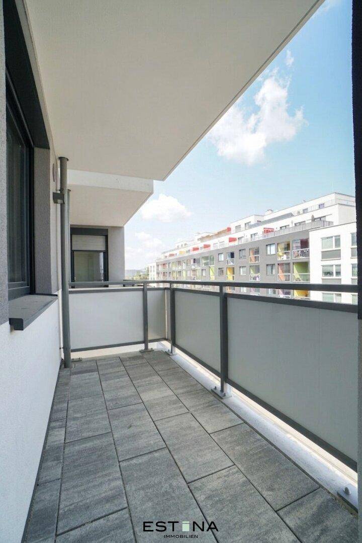 Heller Balkon mit Fliesenboden und Blick auf die umliegenden Gebäude.