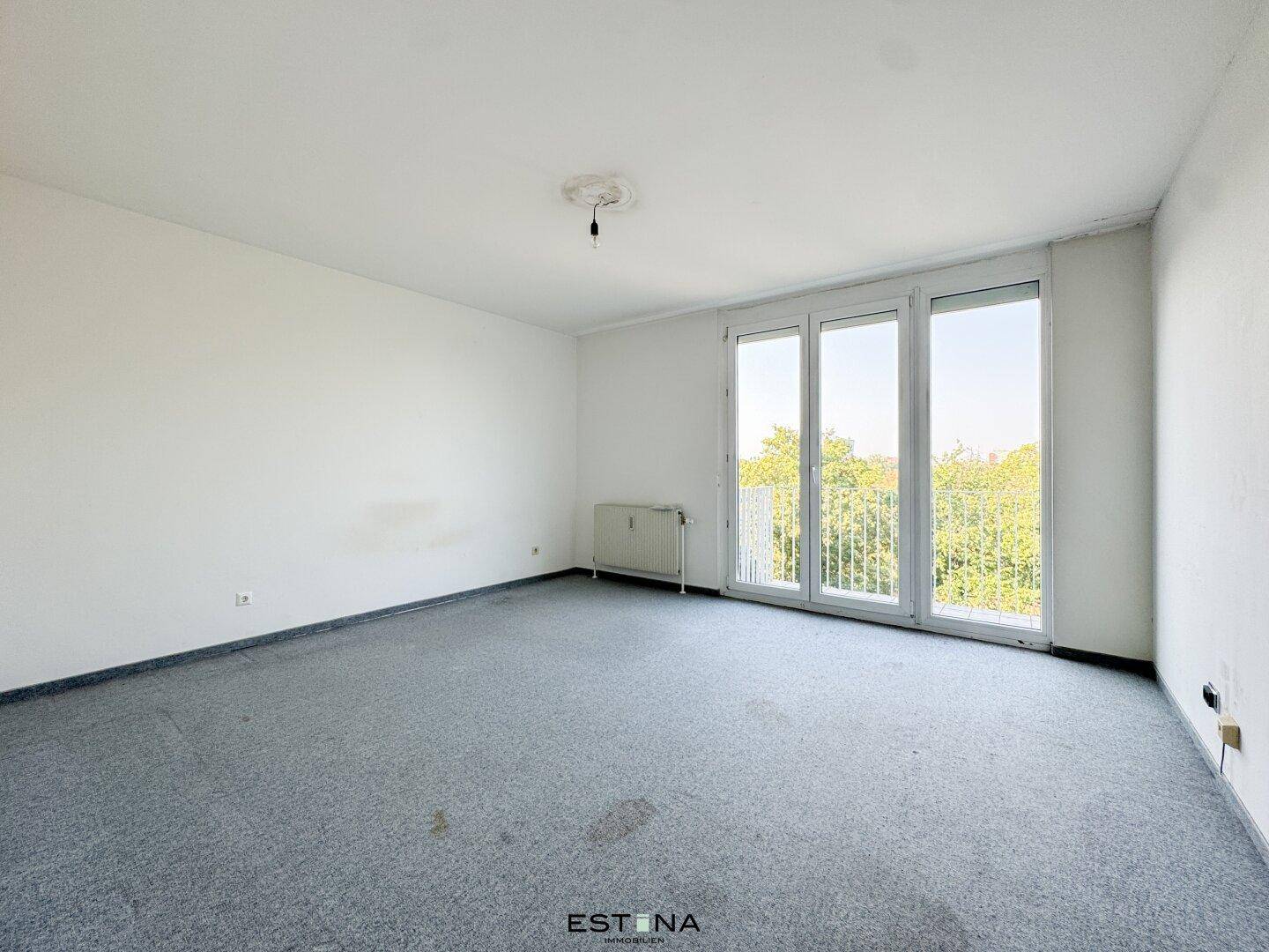 Helles Schlafzimmer mit grauem Teppichboden und großen Fenstern zum französischen Balkon.