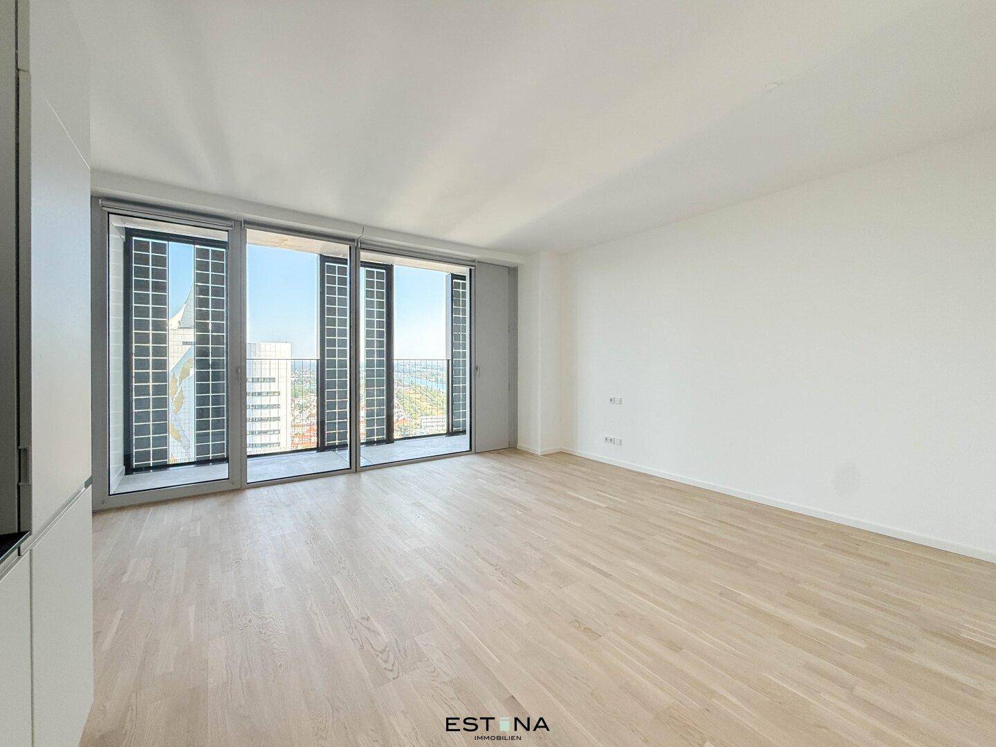 Lichtdurchflutetes Wohnzimmer mit großen Fenstern und Zugang zu einem französischen Balkon.
