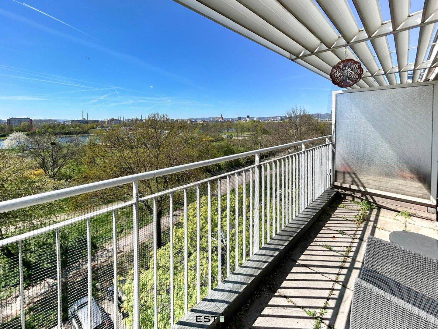 Heller Balkon mit Blick auf einen See und die grüne Umgebung, ideal zum Entspannen im Freien.