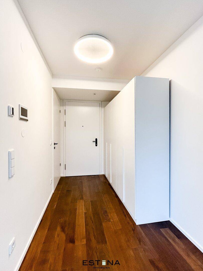 Heller Flur mit praktischen, weißen Einbauschränken und dunklem Holzboden.