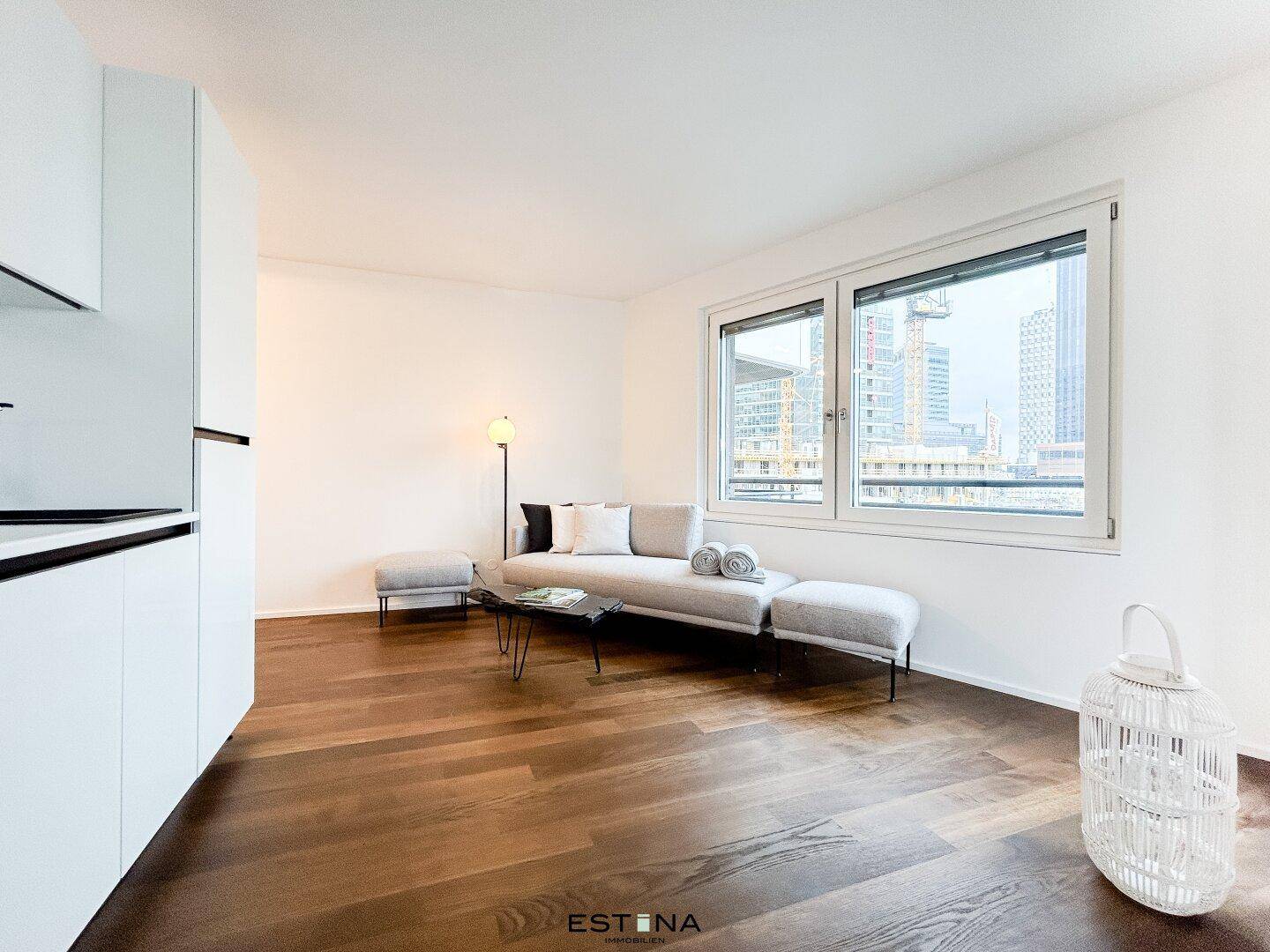 Gemütliches Wohnzimmer mit modernem Sofa, Holzboden und Blick auf die städtische Umgebung.
