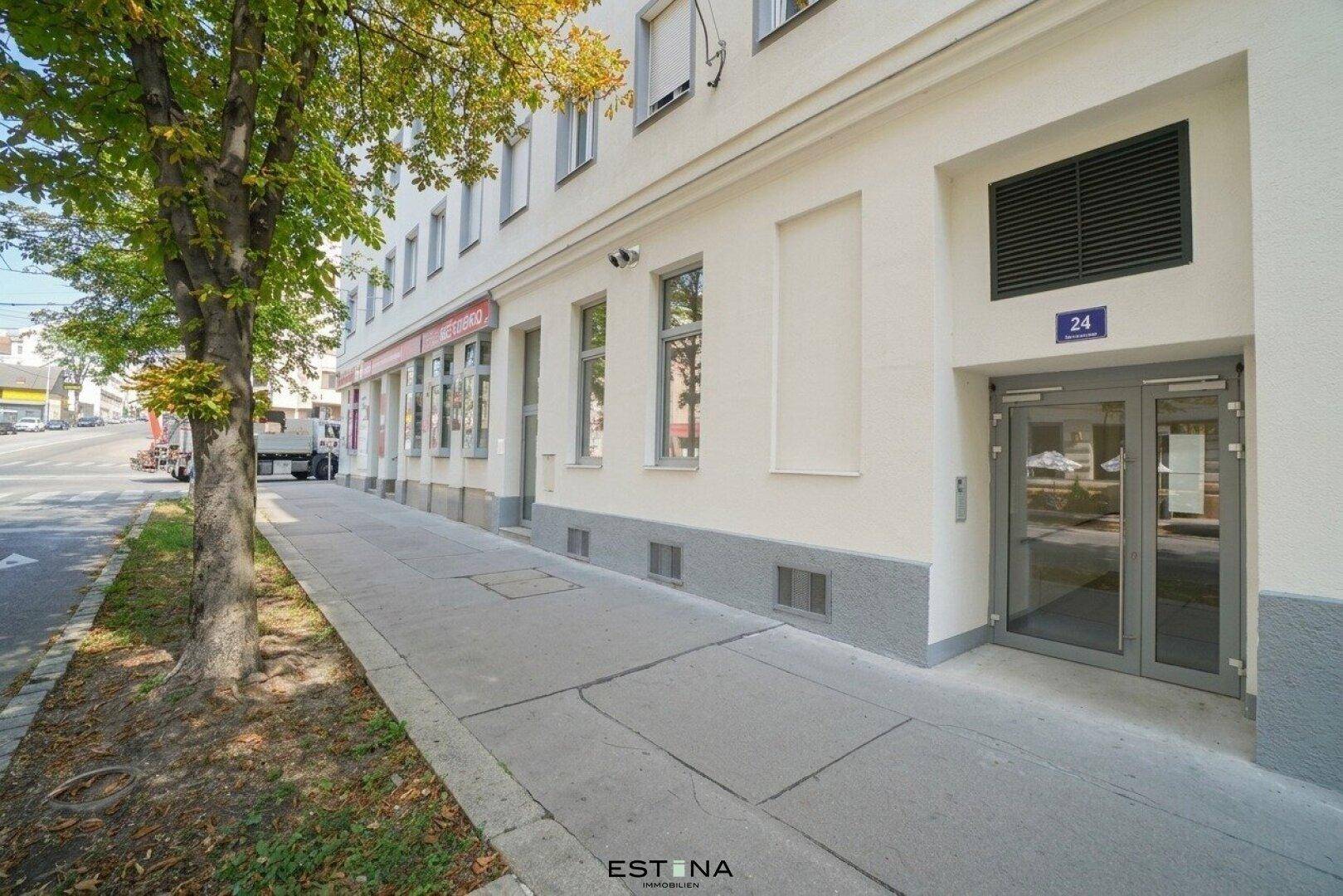 Eingangsbereich eines Mehrfamilienhauses mit Bürgersteig, Rampe und Straßenansicht in der Stadt.