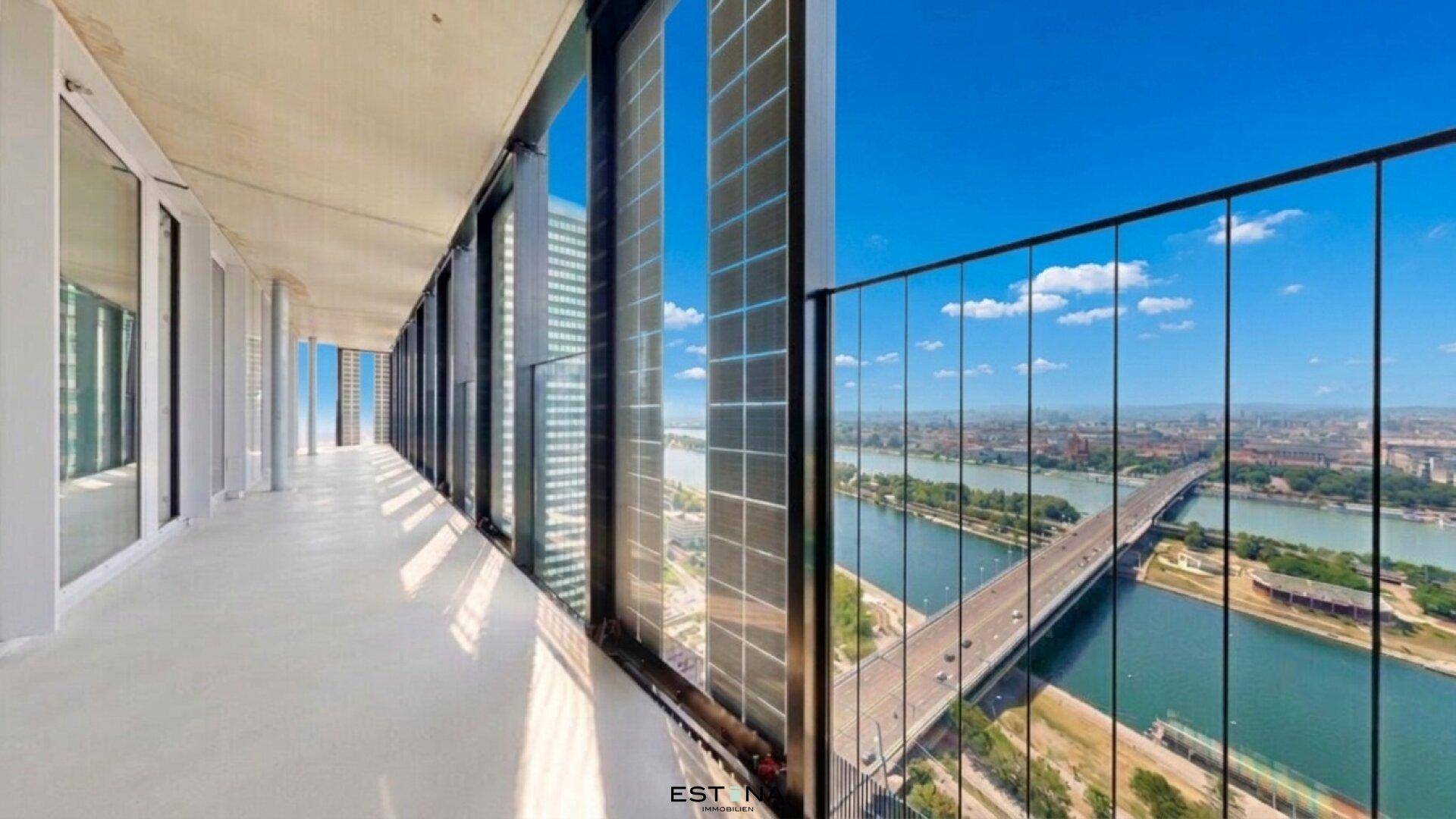 Lange Loggia mit atemberaubendem Stadt- und Flussblick sowie modernem Glasgeländer und viel Tageslicht.