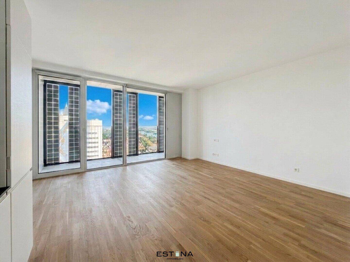 Heller Wohnraum mit großen Fenstern, Holzboden und weitem Blick über die Stadt.