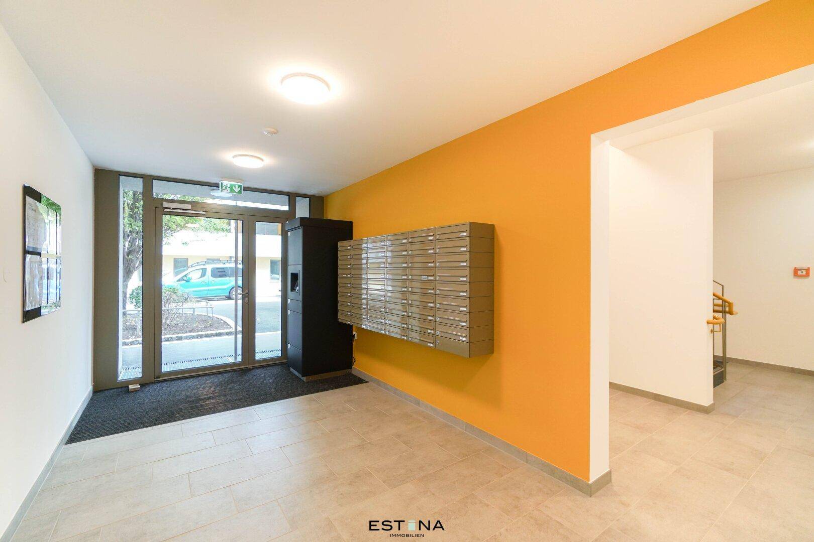 Moderner Eingangsbereich des Gebäudes mit Briefkästen und einer farbigen Akzentwand.