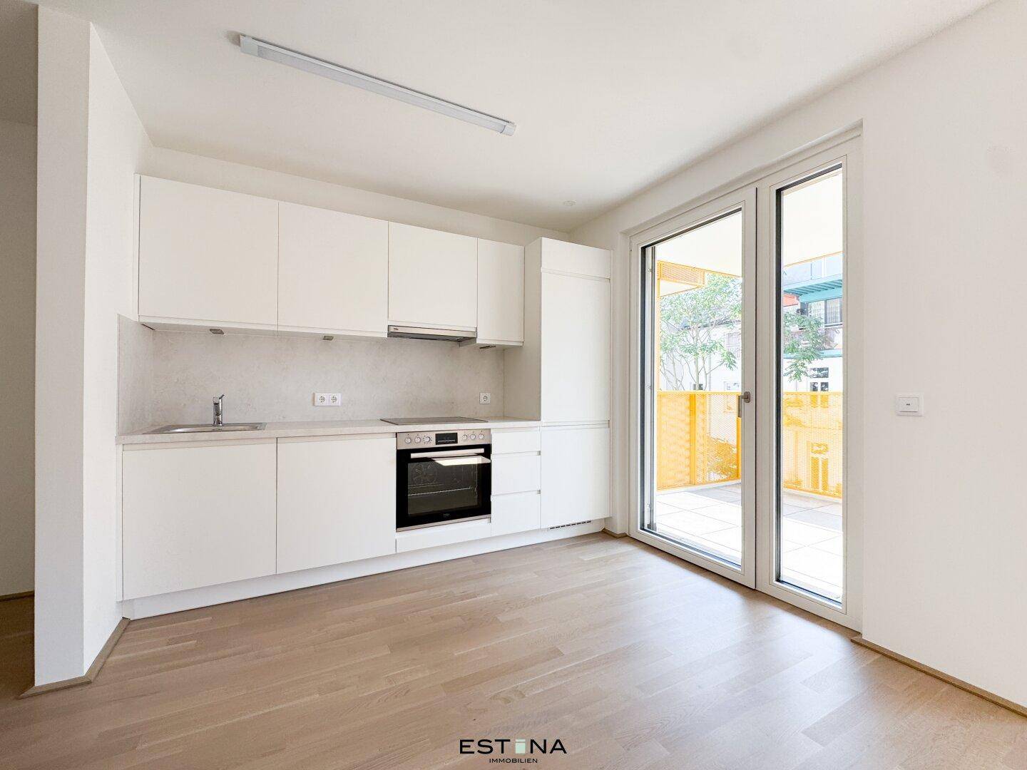 Moderne Einbauküche mit weißen Schränken, integrierten Geräten und Balkonzugang.