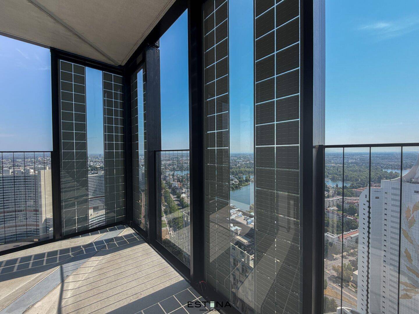 Balkon mit moderner Glasbrüstung und weitem Blick auf die Stadt und die umliegende Landschaft.