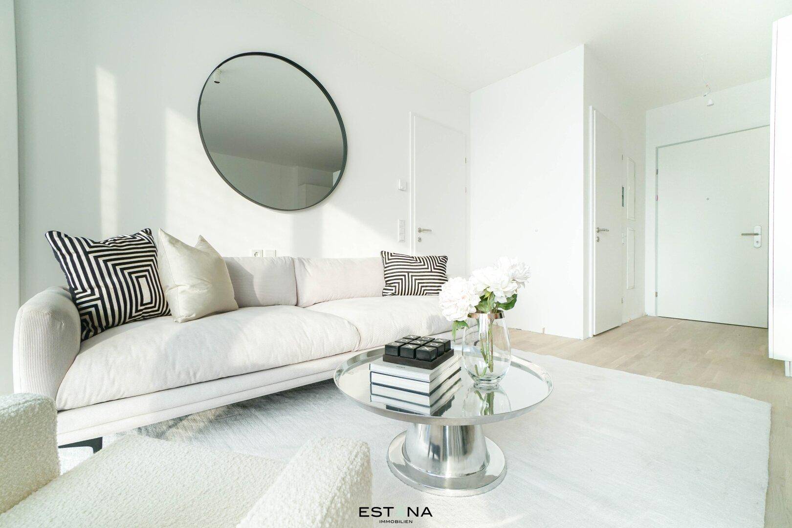 Gemütlicher Wohnbereich mit weißem Sofa, elegantem Couchtisch und dekorativem Wandspiegel.