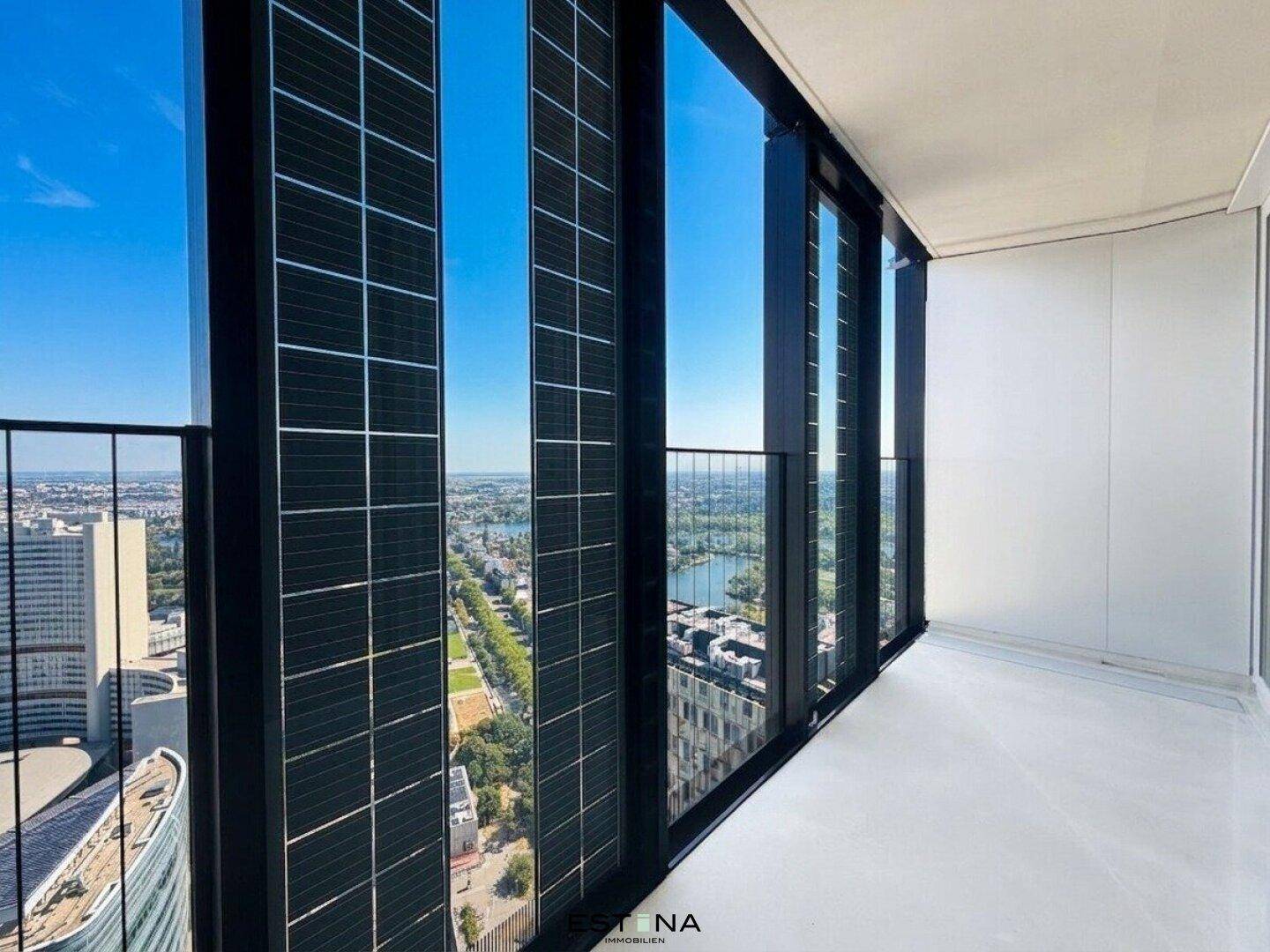 Lichtdurchflutete Loggia mit weitem Blick über die Stadt und grüne Landschaften.