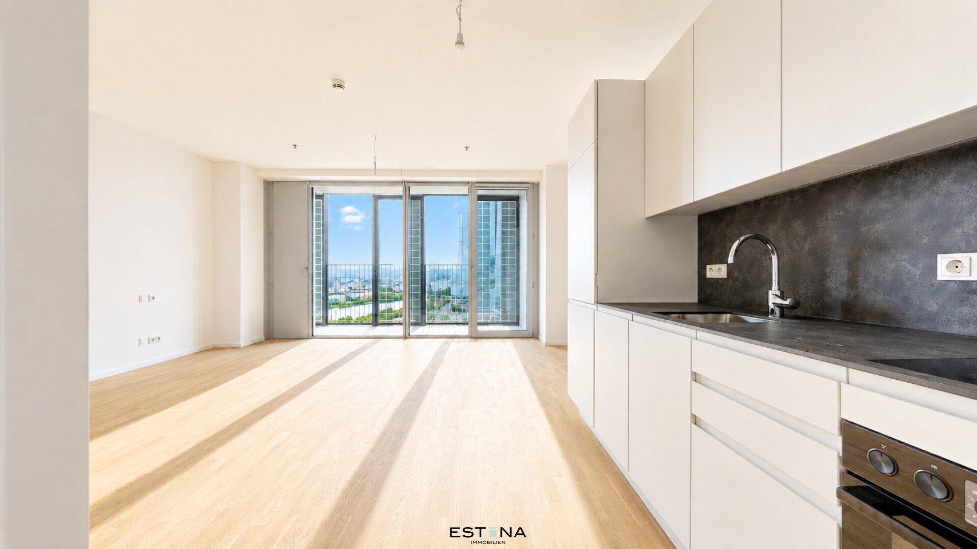 Heller Wohnbereich mit Holzboden, integrierter Küchenzeile und Zugang zu einem Balkon mit Stadtblick.