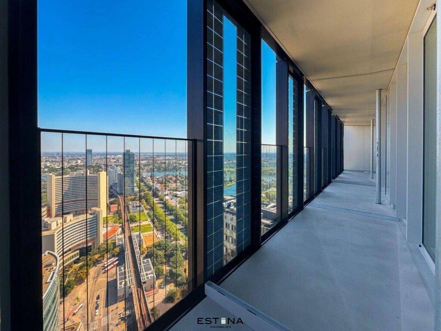Langer Balkon mit Glasbrüstung und beeindruckendem Stadt- und Flussblick von einem Hochhaus.