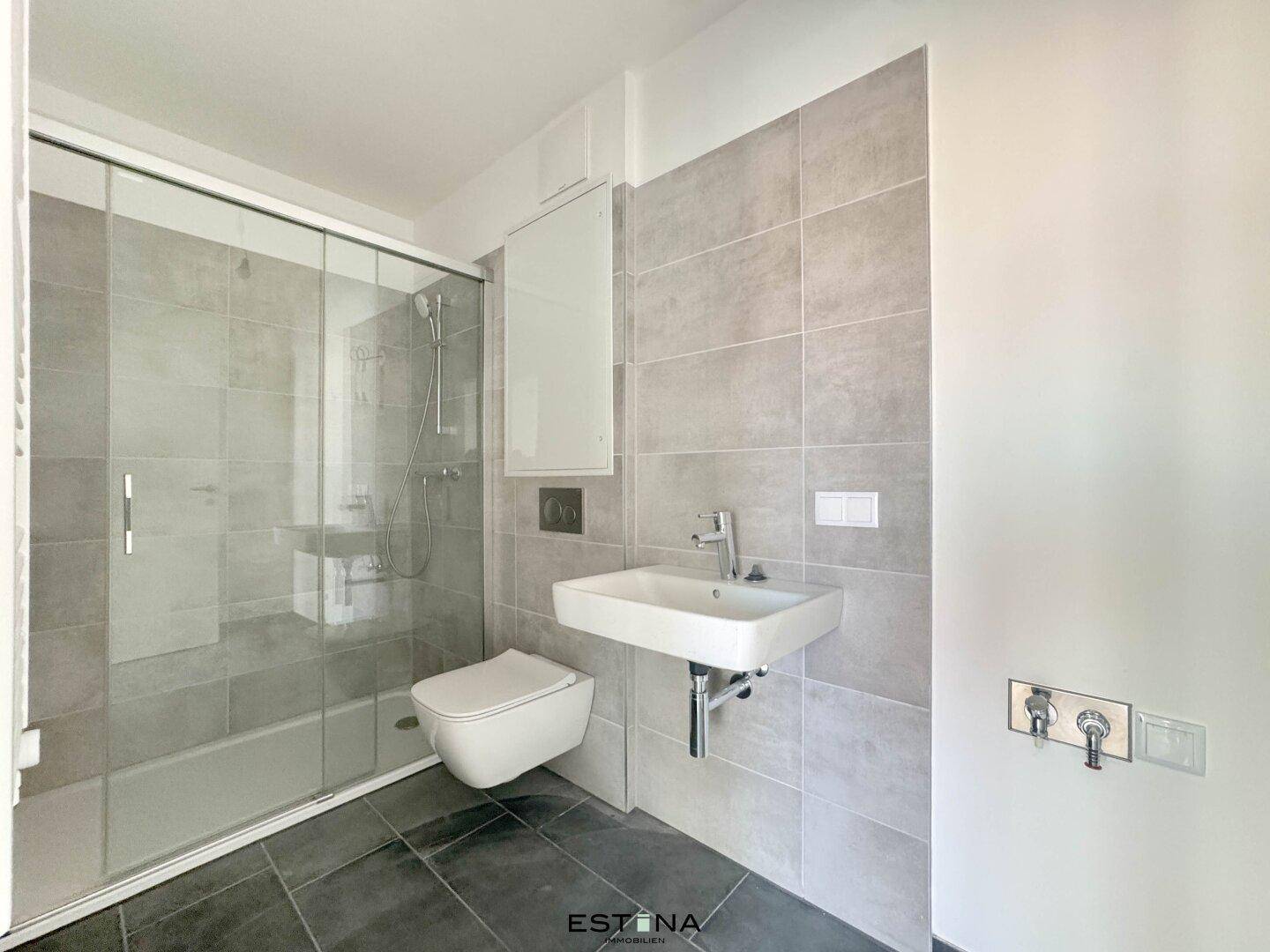 Modernes Badezimmer mit begehbarer Dusche, Wand-WC und grauen Fliesen.
