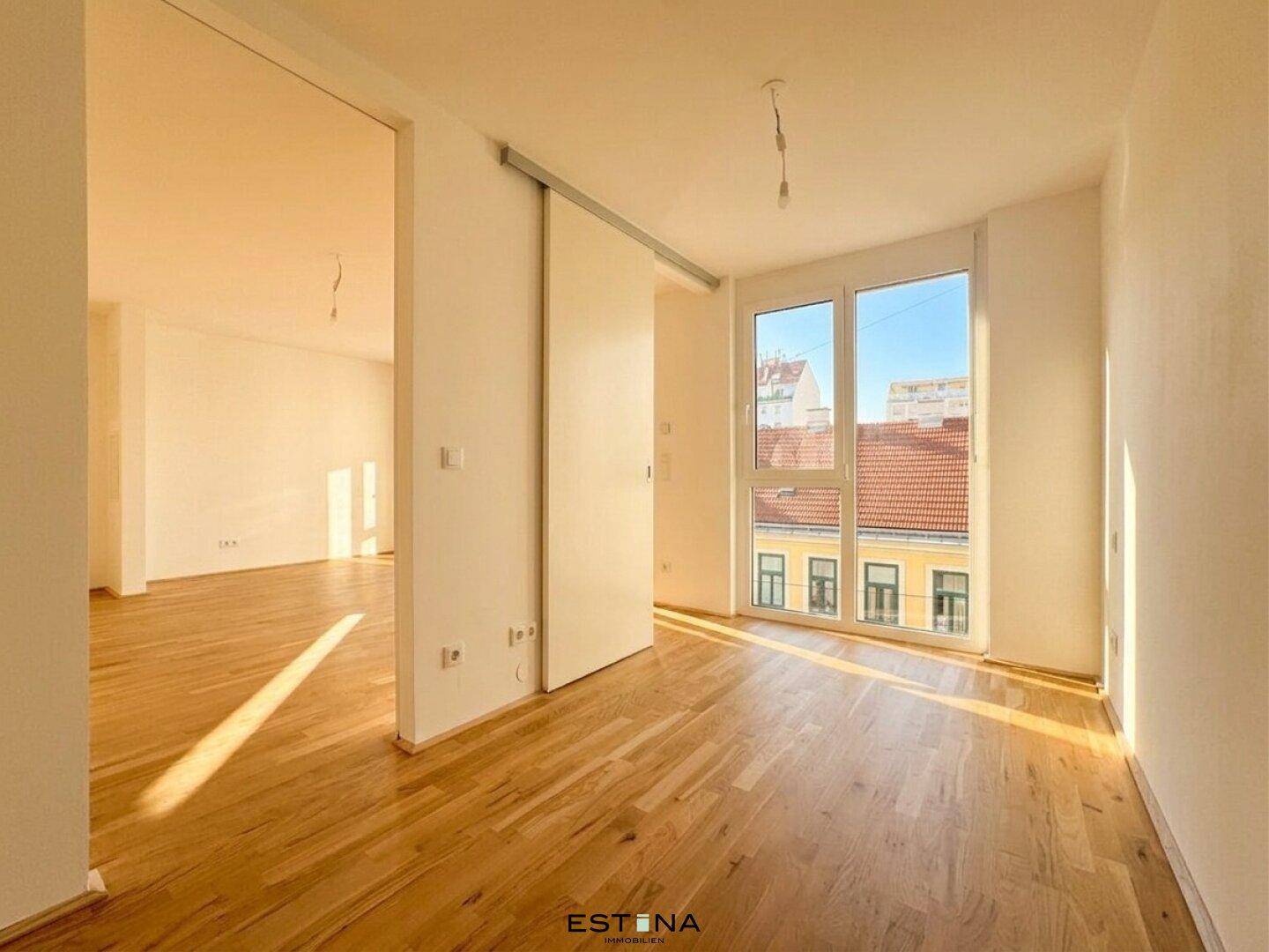 Heller Wohnbereich mit Schiebetür und Holzboden, durchflutet von Sonnenlicht.