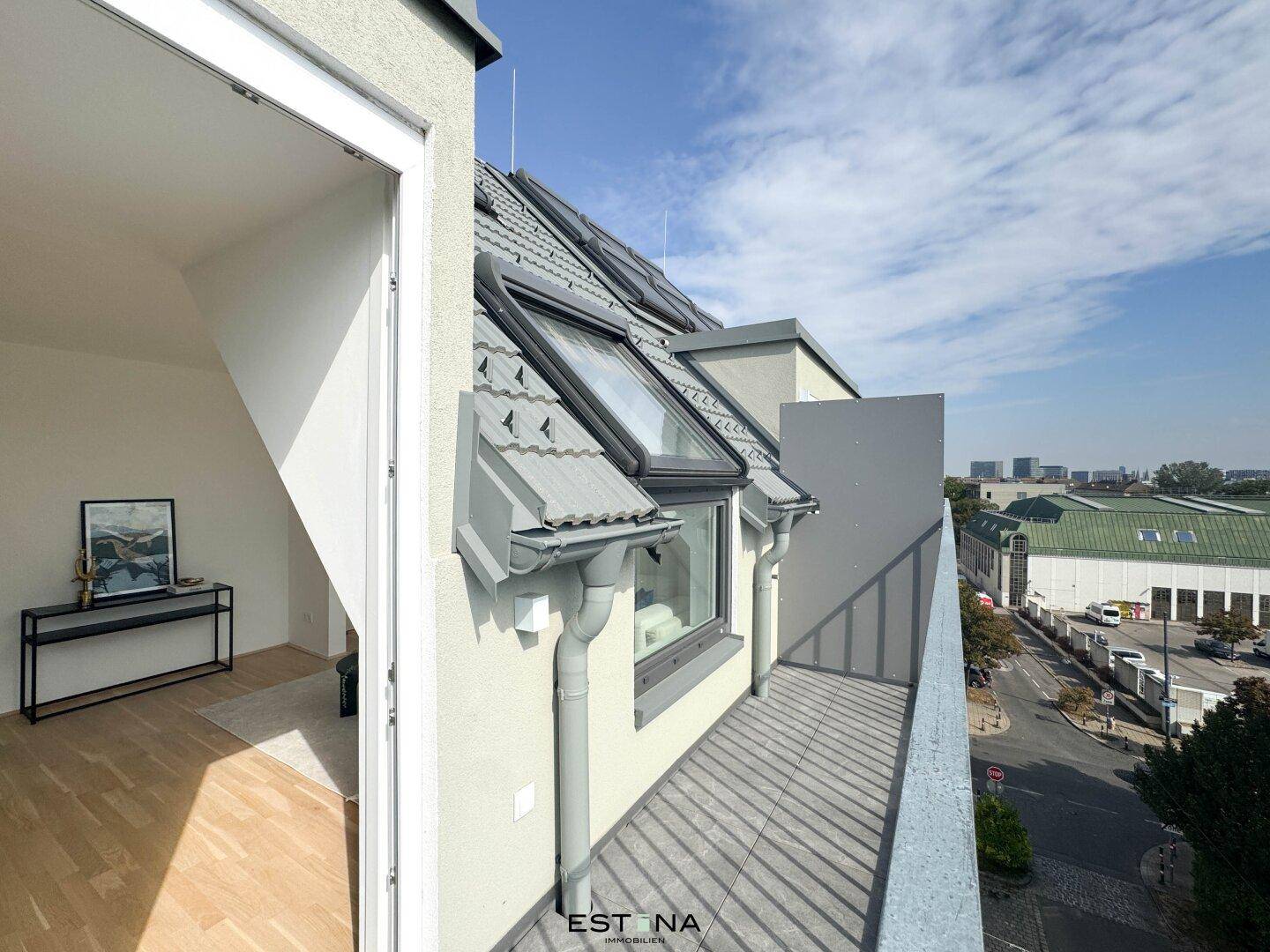 Langer Balkon mit Fliesenboden und Blick auf die umliegende Stadtbebauung.