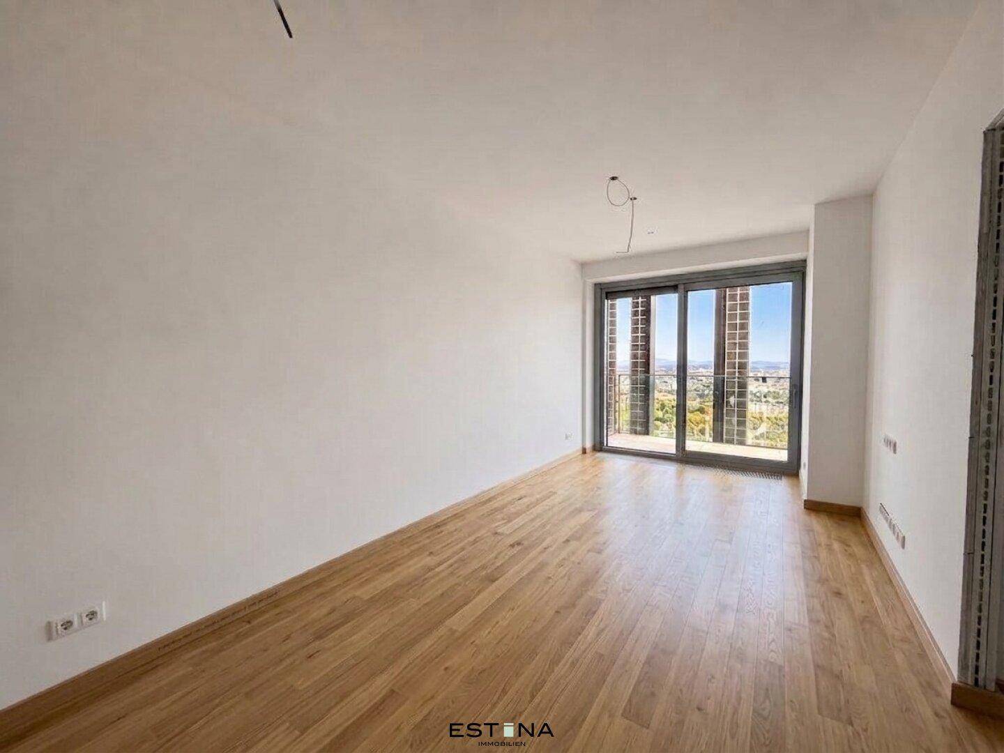 Geräumiger Raum mit Holzboden und Schiebetüren, die Zugang zu einem Außenbereich bieten.