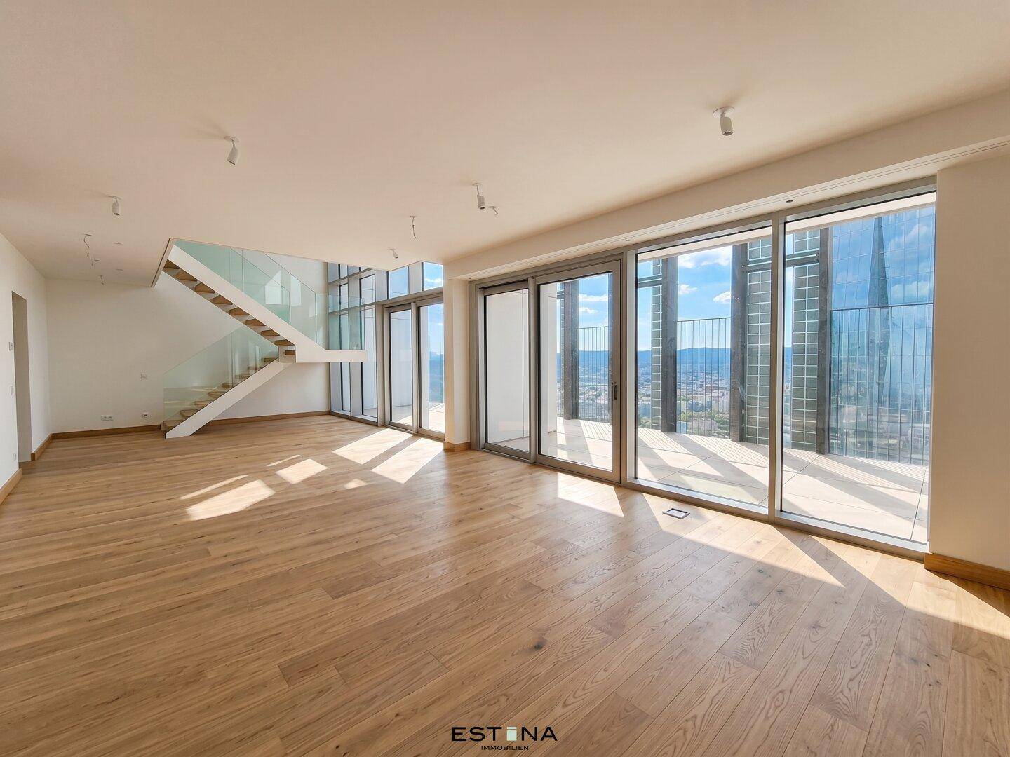 Lichtdurchfluteter Wohnbereich mit moderner Treppe, Glasgeländer und Panoramablick auf die Stadt.