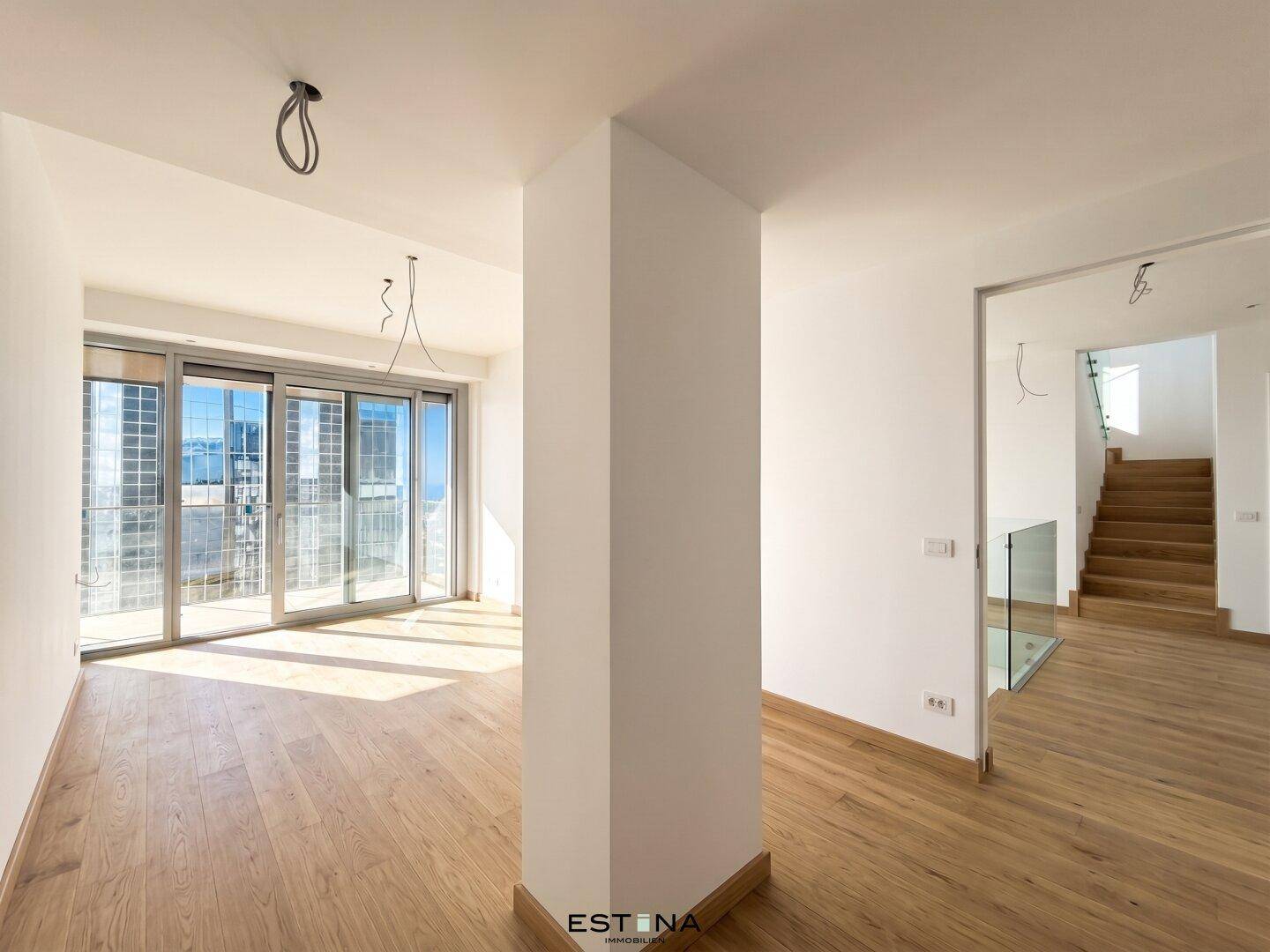 Heller Eingangsbereich mit Holzboden und Blick auf eine moderne Holztreppe.