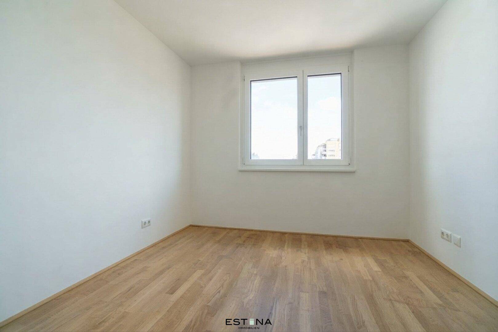 Helles Zimmer mit Holzboden und weiß gestrichenen Wänden, ideal als Schlaf- oder Arbeitszimmer.