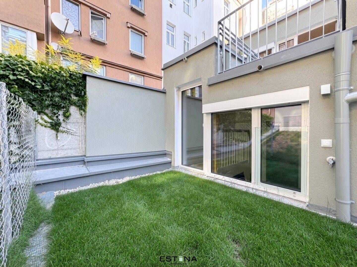 Kleiner privater Gartenbereich mit Rasenfläche und Zugang zu einem Wohnraum im Erdgeschoss.