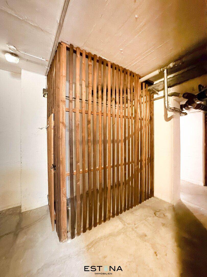 Kellerabteil mit Holzlattenwänden und Betonboden, bietet zusätzlichen Stauraum für Bewohner.