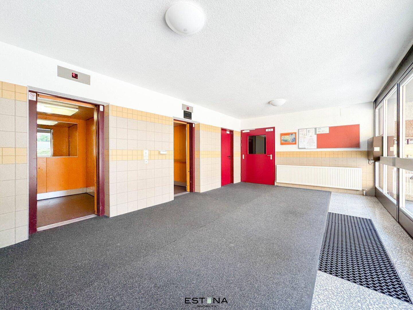 Heller Eingangsbereich mit zwei Aufzügen und Fliesenboden in einem Mehrfamilienhaus, gut gepflegt.