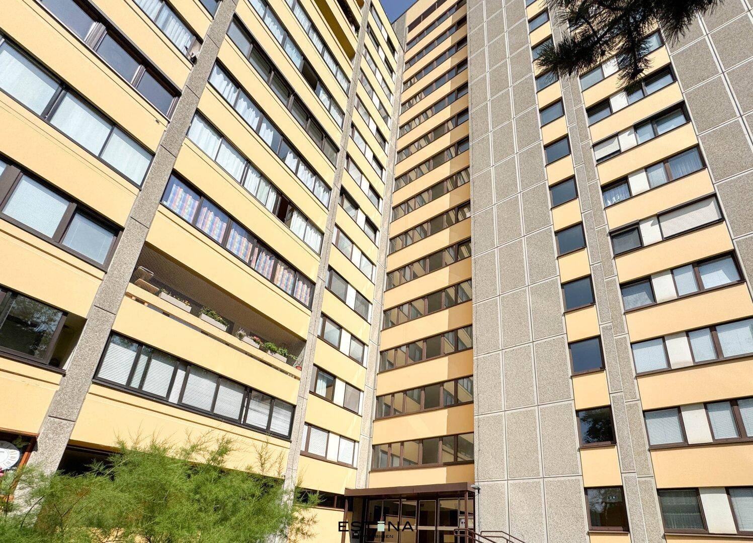 Hohes Wohngebäude mit vielen Fenstern und Balkonen unter blauem Himmel, moderne Architektur.