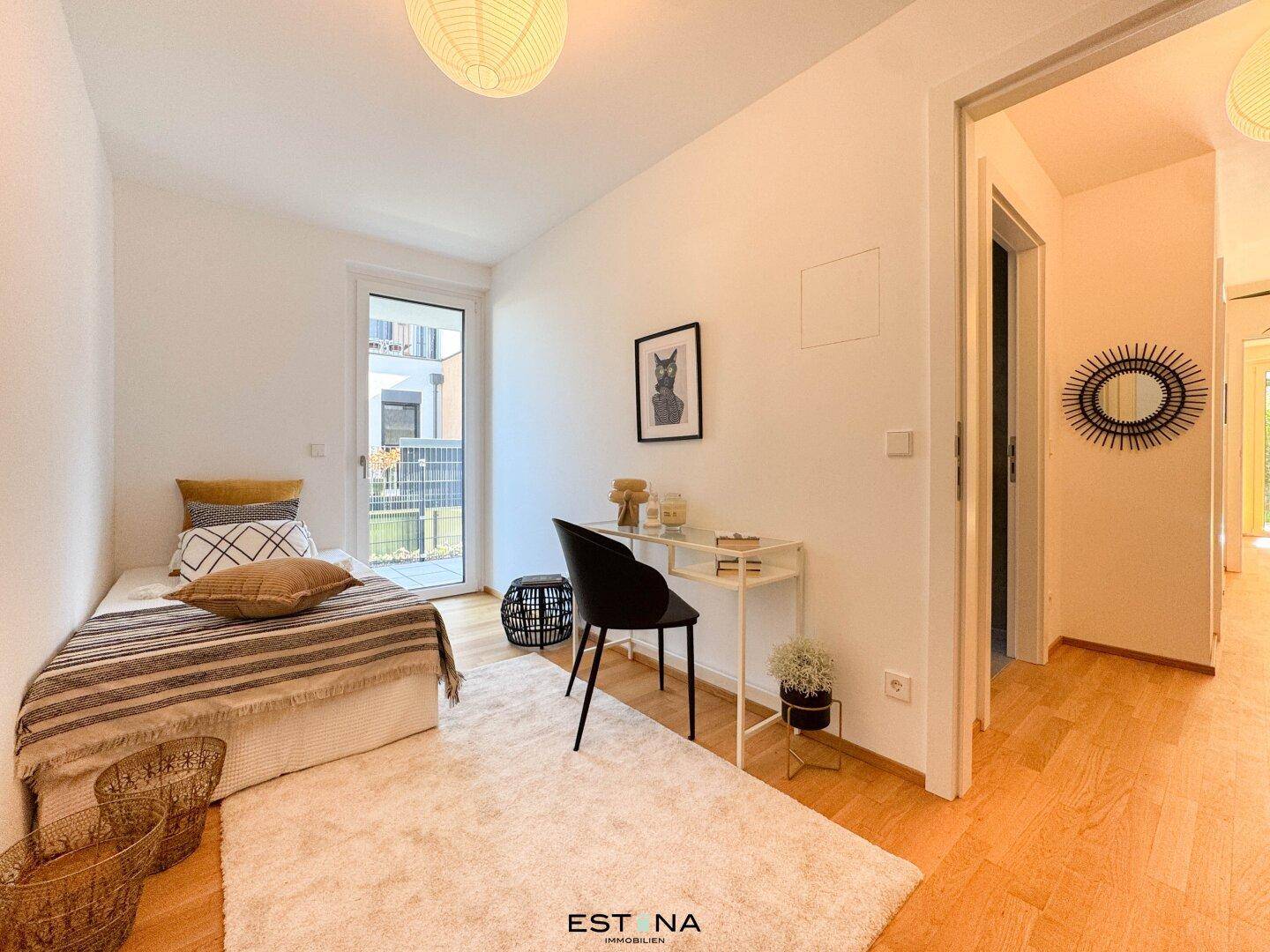 Freundliches Schlafzimmer mit Einzelbett, Schreibtisch und Zugang zu einem Außenbereich, ideal als Gästezimmer.
