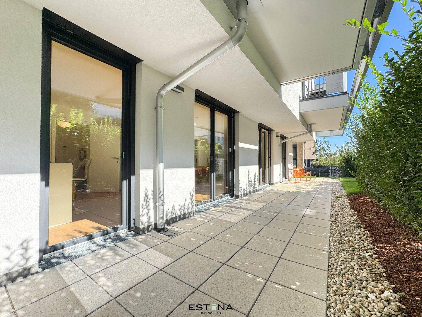 Lange, gepflasterte Terrasse im Erdgeschoss mit großen Glasfronten und Zugang zu den Wohnbereichen.