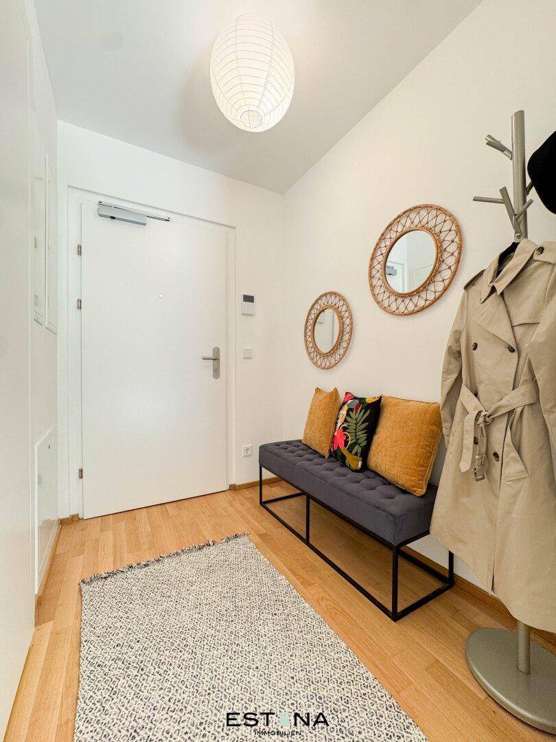Heller Eingangsbereich mit Garderobe, Sitzbank und Holzboden, der einladend wirkt.