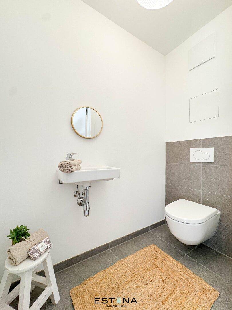 Modernes Gäste-WC mit wandhängendem WC und kleinem Waschbecken, in schlichtem Design gehalten.