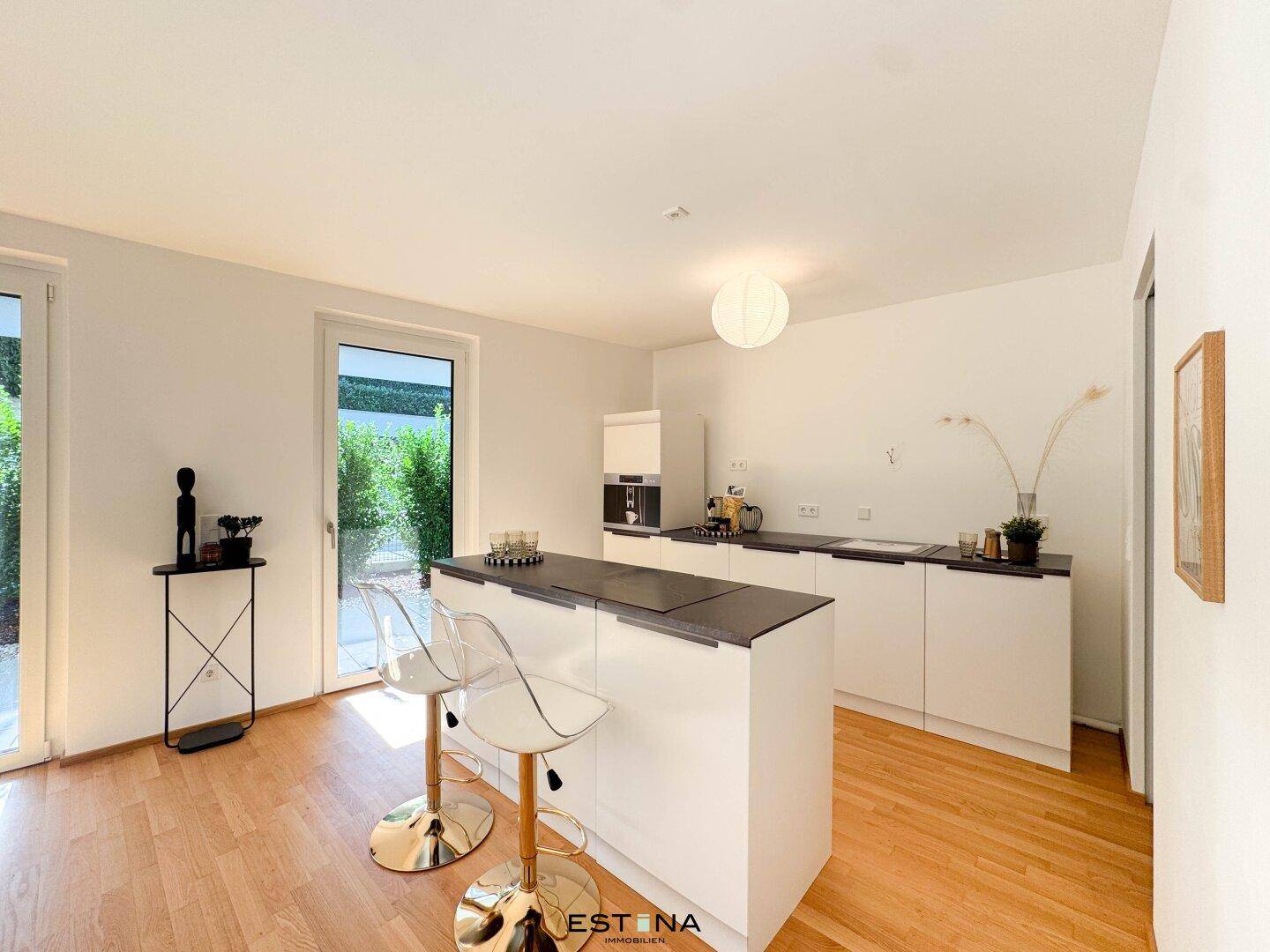 Moderne Einbauküche mit weißer Front, dunkler Arbeitsplatte und einer praktischen Kücheninsel mit Barhockern.