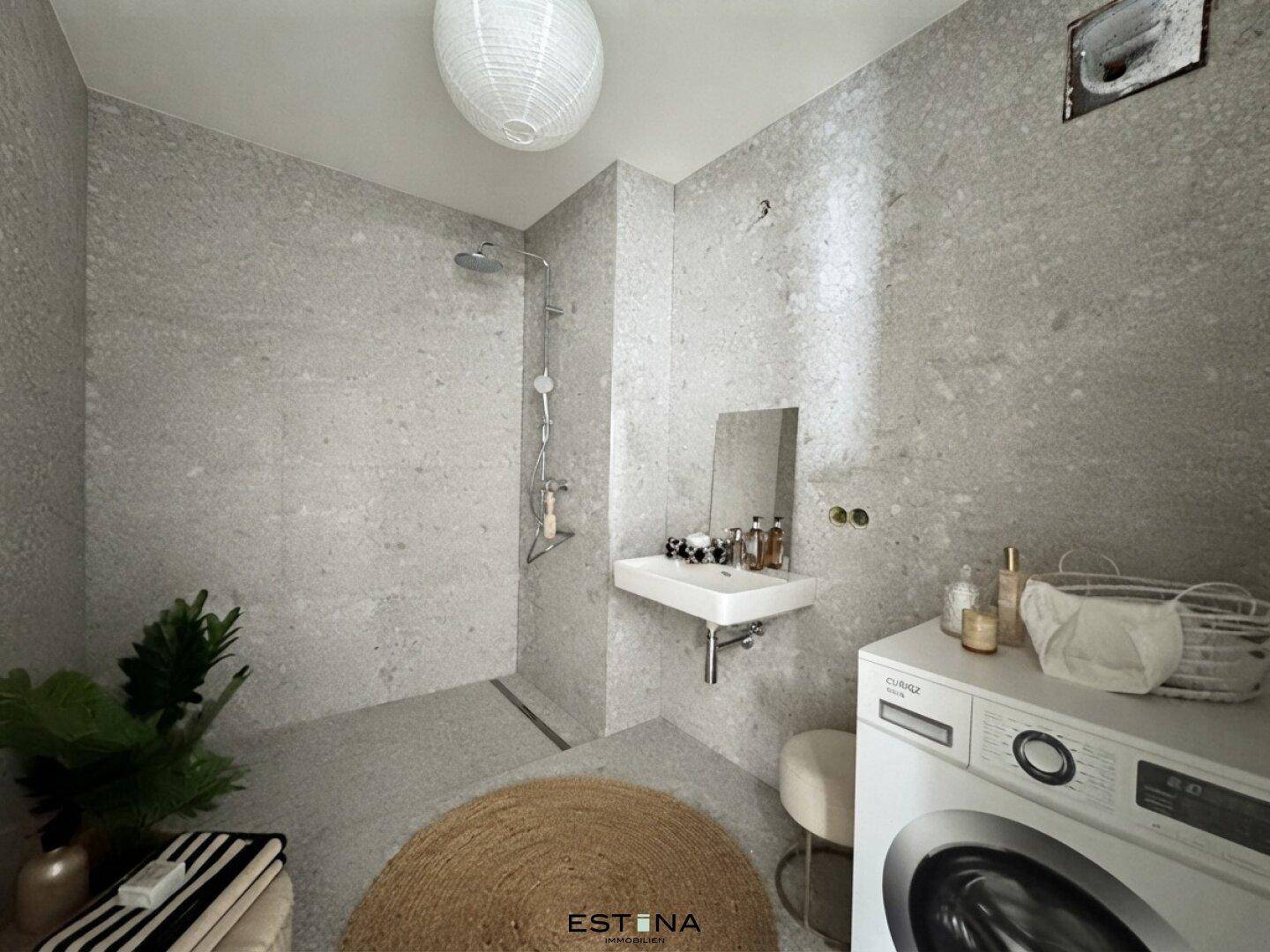 Zeitgemäßes Badezimmer mit großer Dusche, Waschbecken und integrierter Waschmaschine.