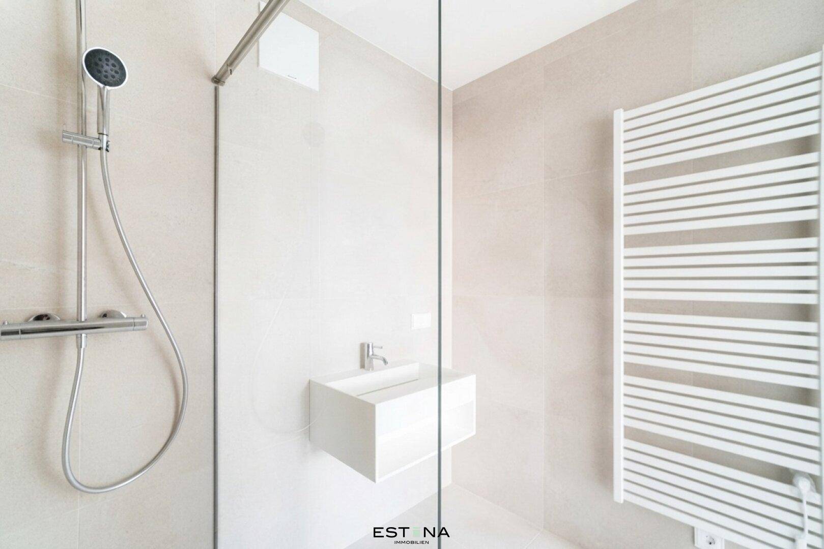 Modernes Badezimmer mit ebenerdiger Dusche, Glasabtrennung und beheiztem Handtuchhalter.