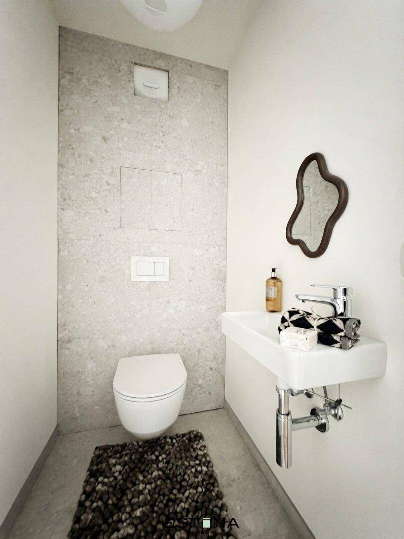 Separates Gäste-WC mit modernem Design, Wand-WC und kleinem Waschbecken.