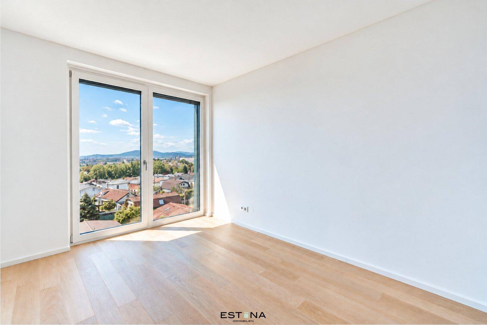 Helles Zimmer mit Parkettboden und großem Fenster, das einen weiten Blick über die Umgebung bietet.
