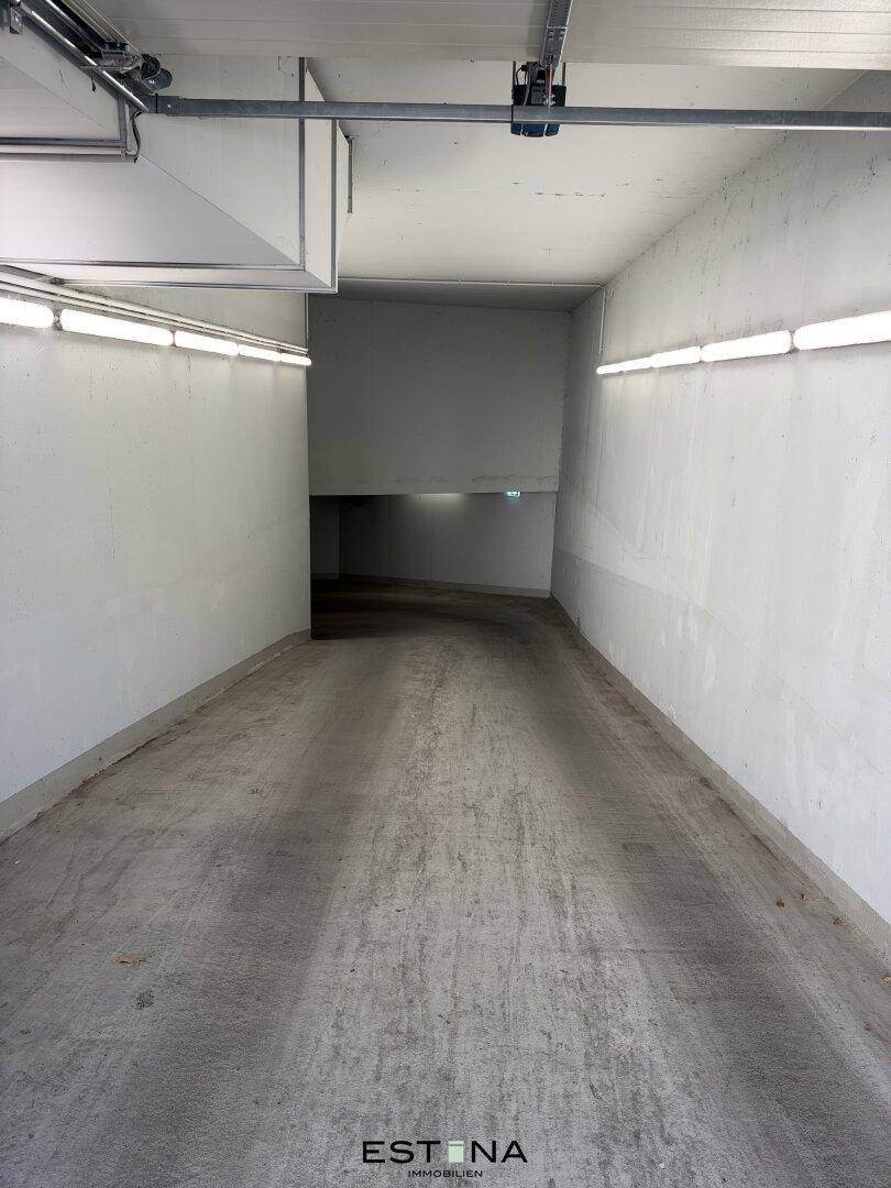 Zufahrtsrampe zur Tiefgarage mit hellen Wänden und durchgehender Beleuchtung.