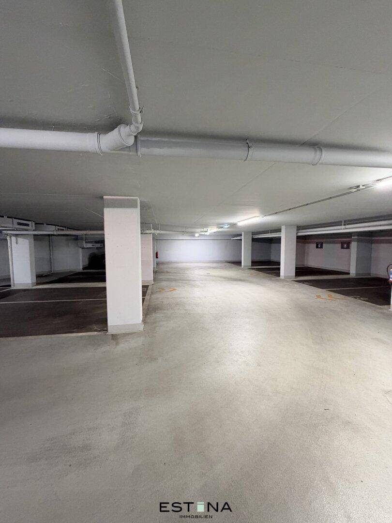 Geräumige und saubere Tiefgarage mit Betonboden und effizienter Deckenbeleuchtung.