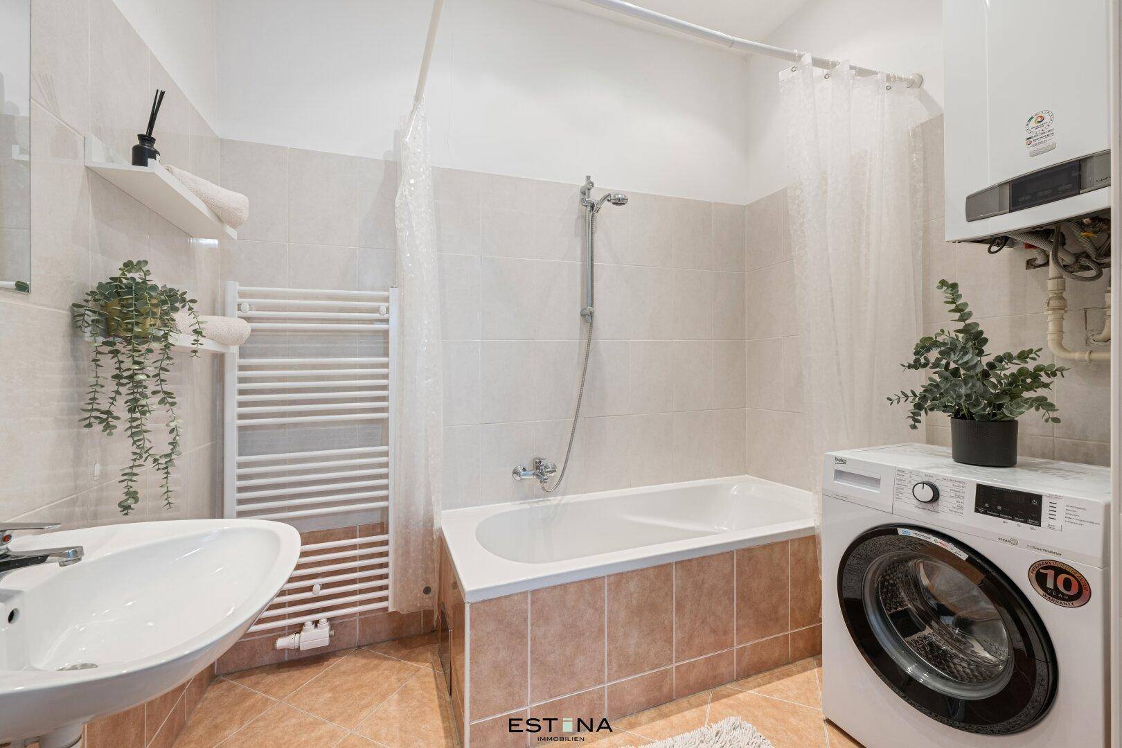 Funktionales Badezimmer mit Badewanne, Waschbecken, Waschmaschine und Handtuchheizkörper.