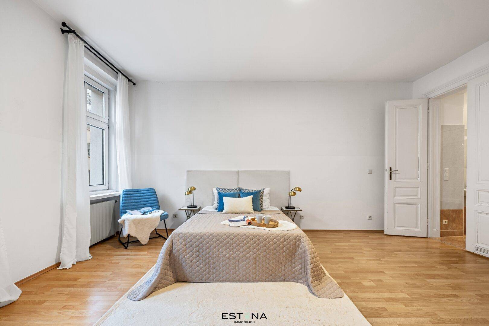 Ruhiges Schlafzimmer mit Holzboden, großem Bett und zwei Fenstern für viel Tageslicht.