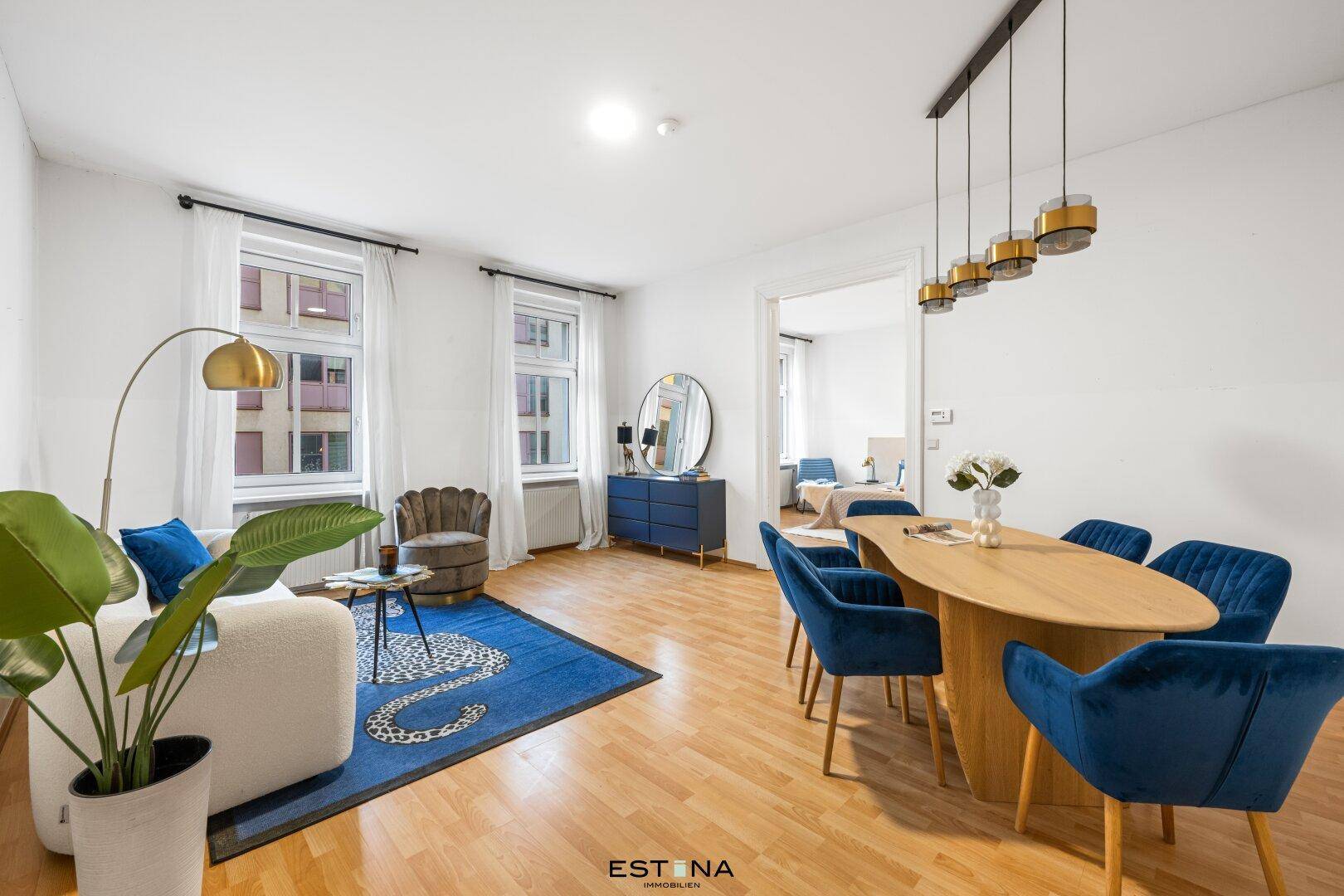 Geräumiger Wohn-Essbereich mit Holzboden, modernem Esstisch und blauen Samtstühlen.
