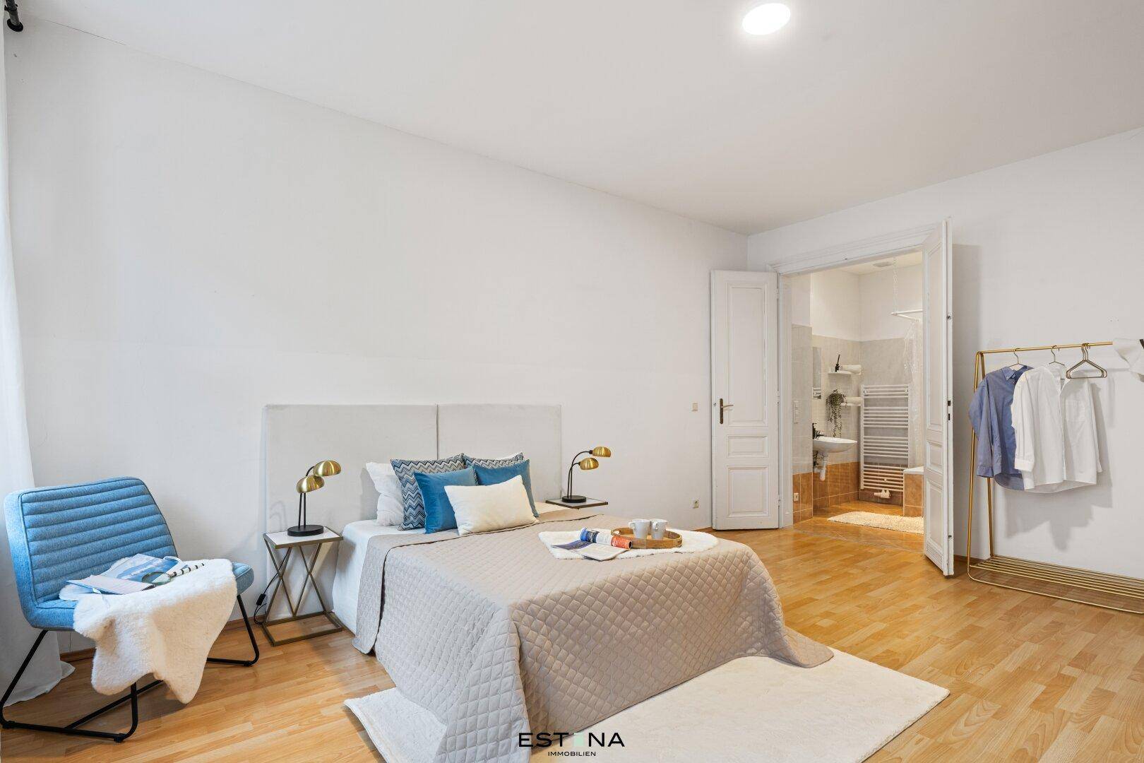 Schlafzimmer mit Holzboden, Doppelbett und direktem Zugang zum Badezimmer.