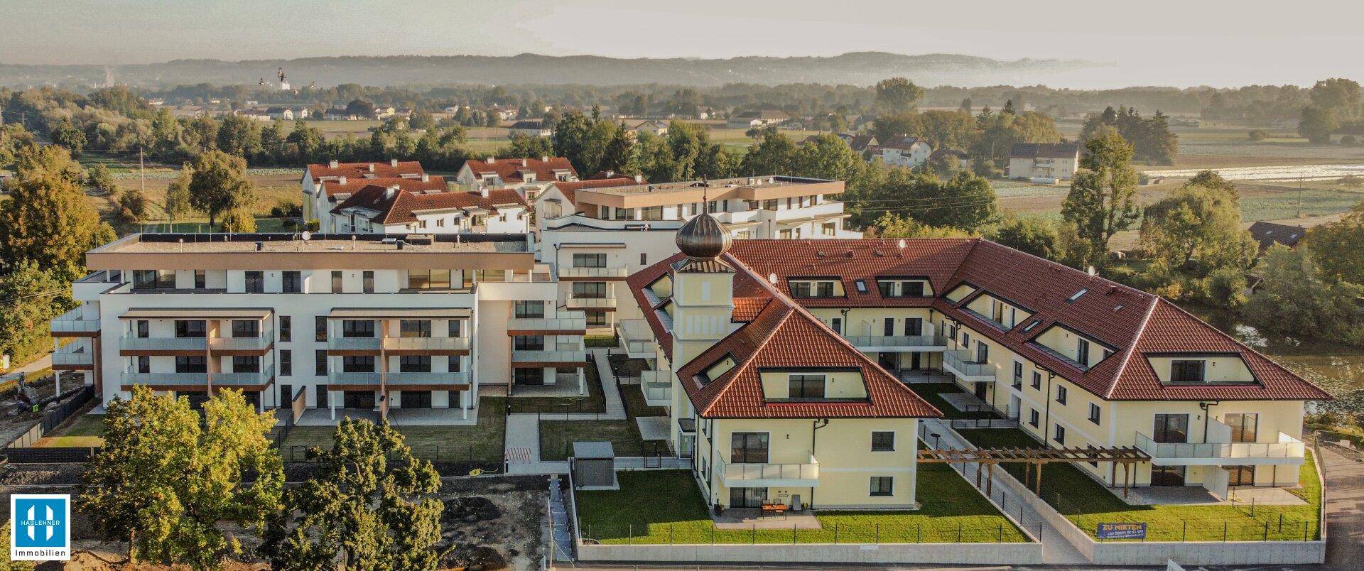Luftaufnahme des Wohnkomplexes mit umliegender Landschaft und weiteren Gebäuden.