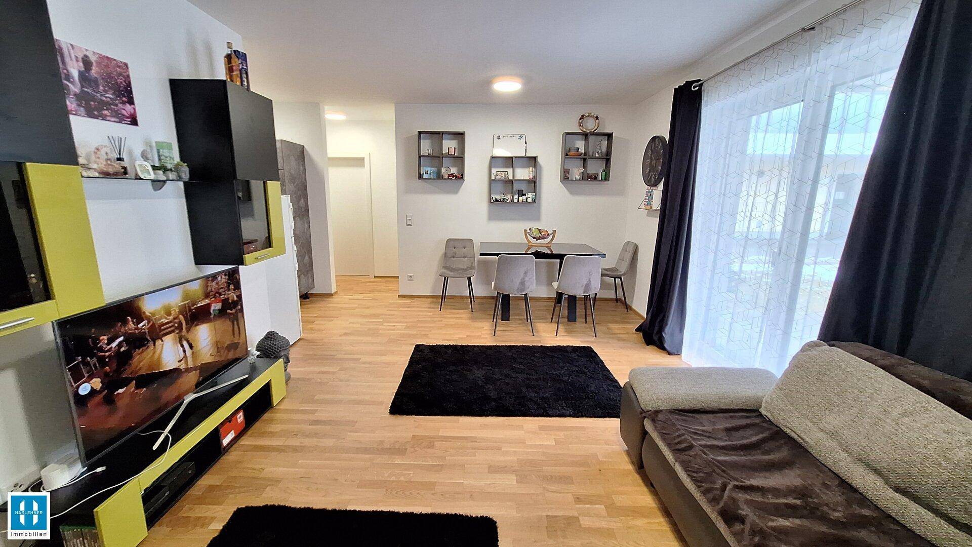 Gemütlicher Wohn-Essbereich mit Holzboden, Sofa, Fernseher und Esstisch für gesellige Stunden.