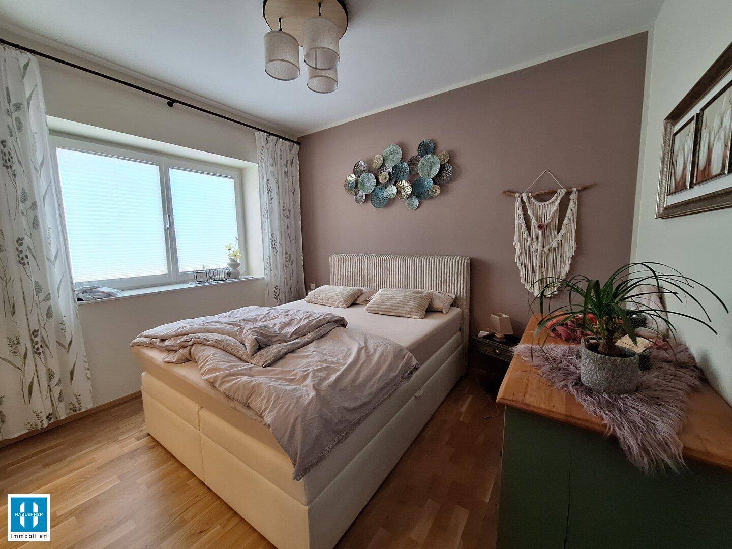 Gemütliches Schlafzimmer mit Doppelbett, Holzboden und großem Fenster für viel Licht.