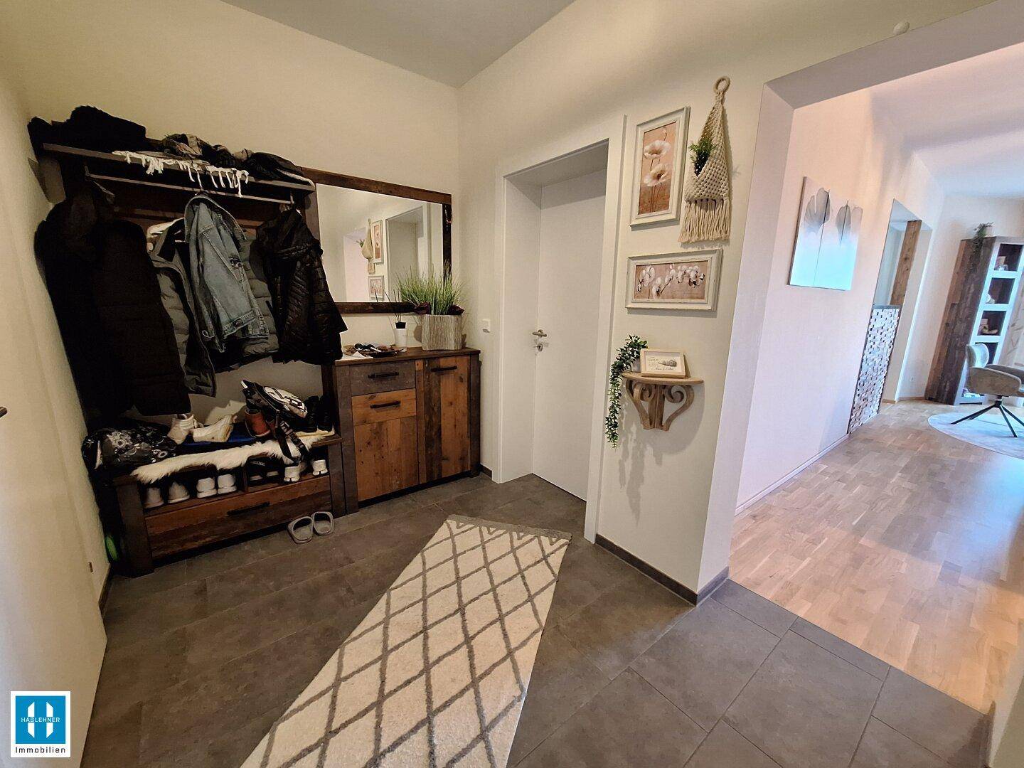 Eingangsbereich mit Garderobe, Spiegel und Fliesenboden, der zu den Wohnräumen führt.
